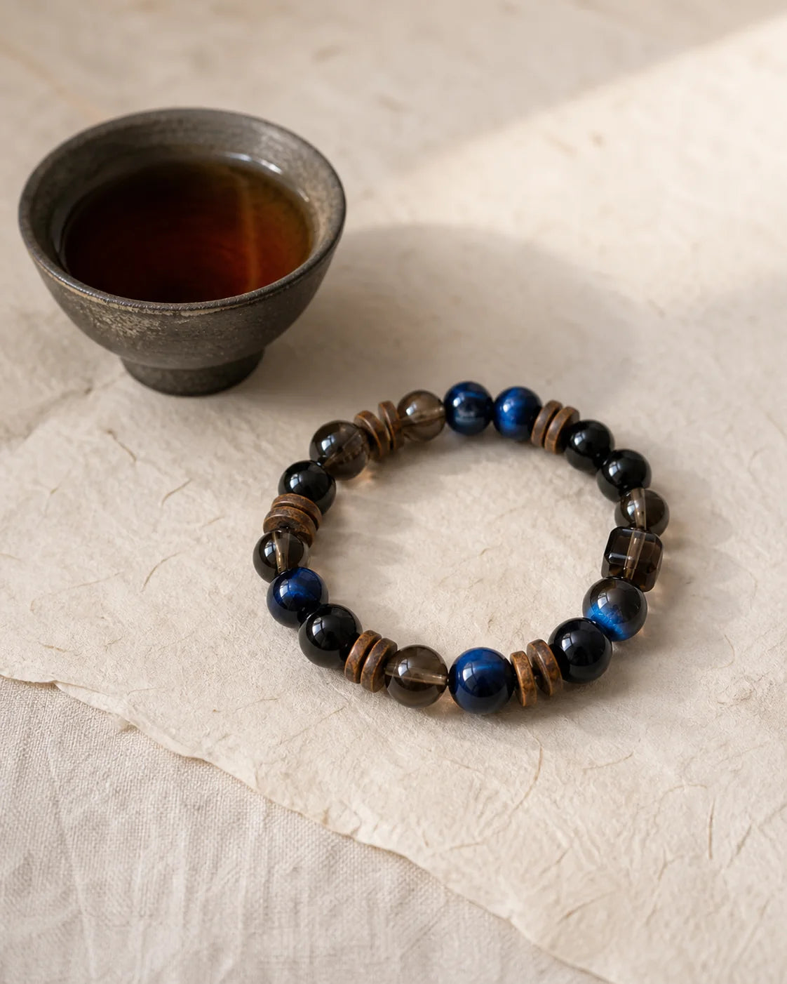 Ink Pu’er bracelet beside a tea cup