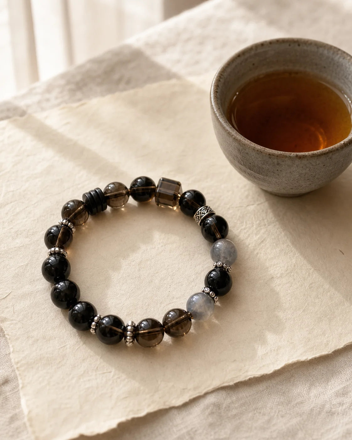Moonlight Aged Dark Tea bracelet beside a tea cup