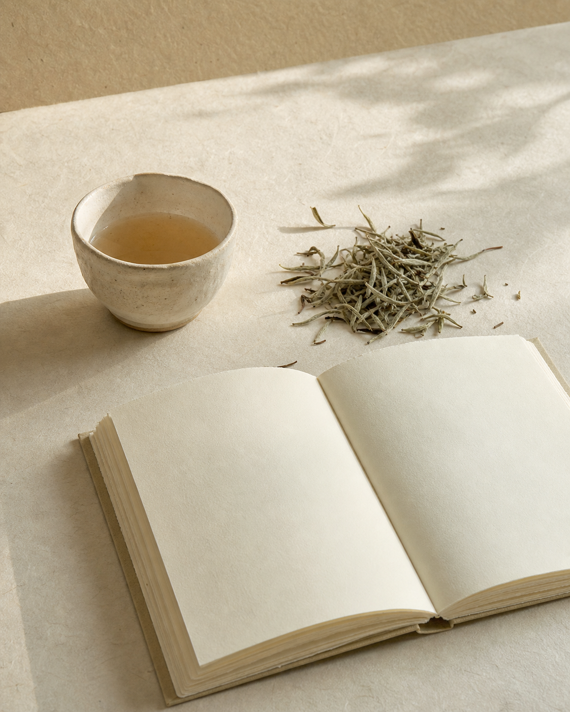 White tea leaves, a tea cup, and an open notebook