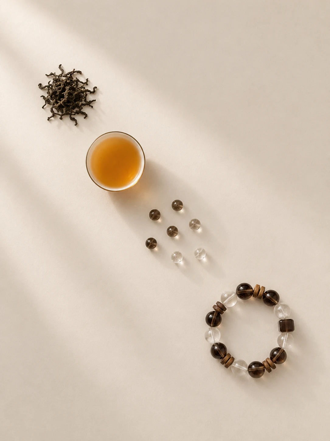 Tea, loose beads, and a smoky quartz bracelet on warm paper